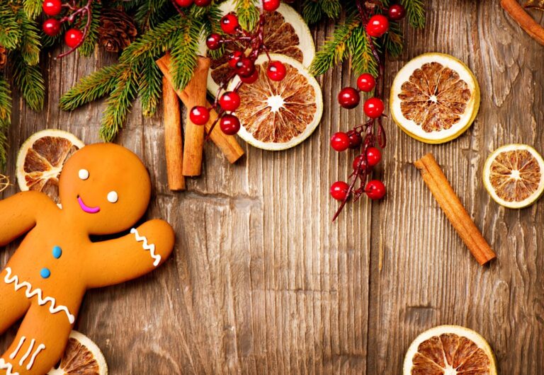 holiday background with fir tree sprigs, red berries, dried orange slices, and a gingerbread man