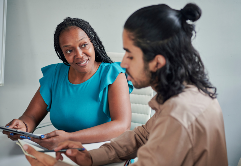 a smiling older person working alongside a younger person in an office