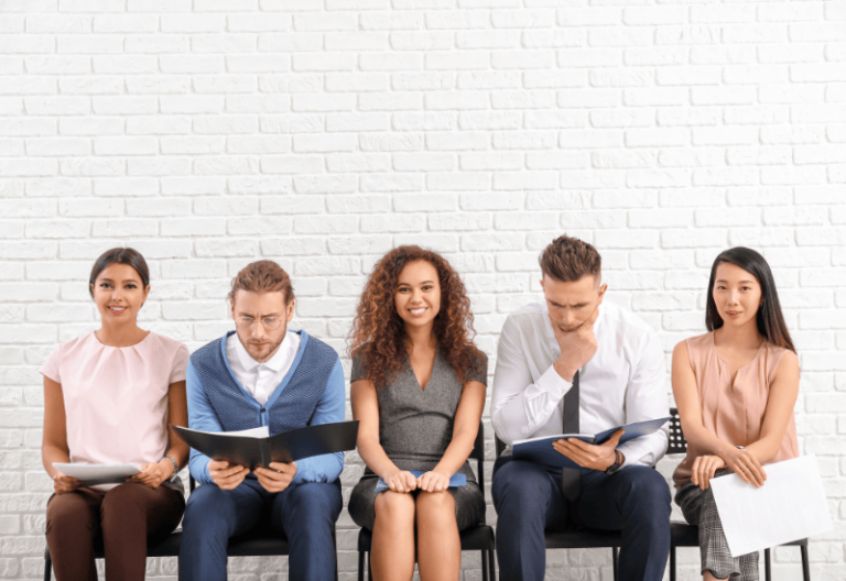 5 people seated in a row waiting for a job interview